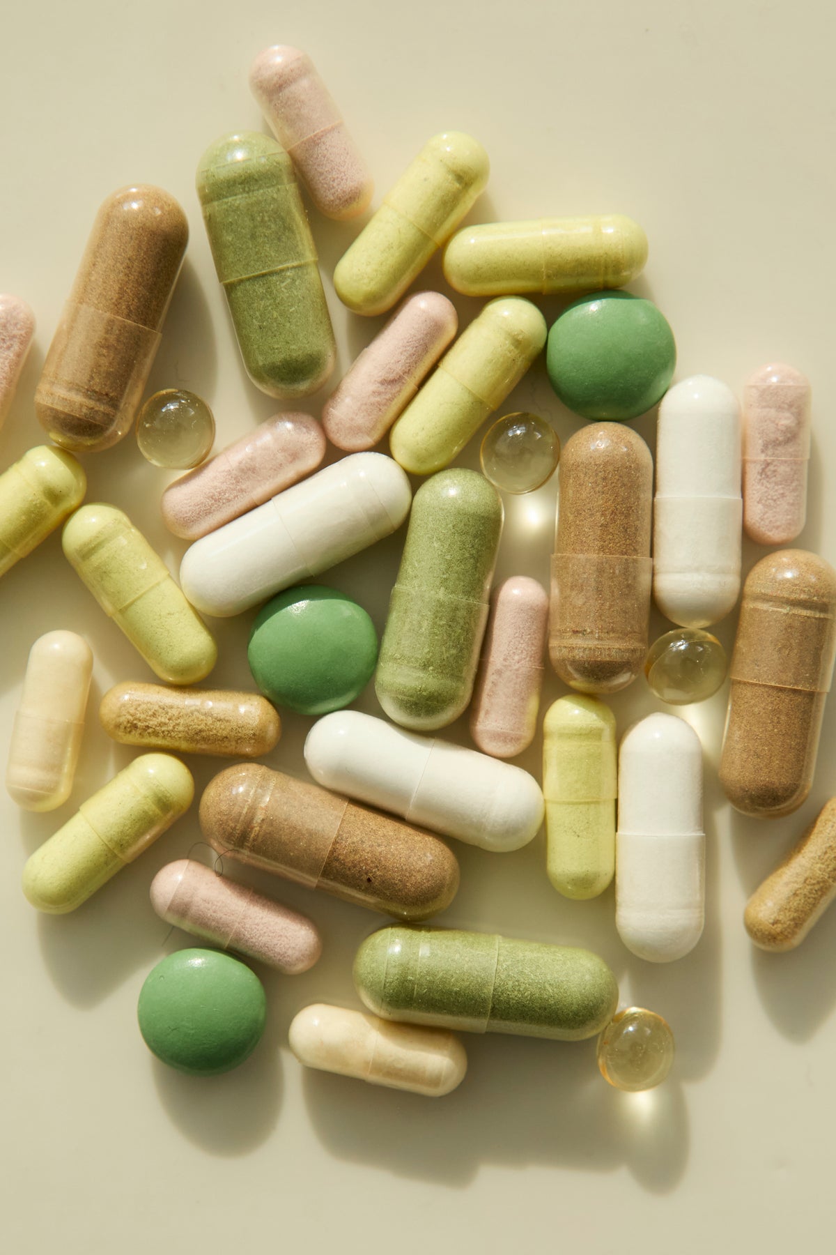 Pills and capsules on a cream background.